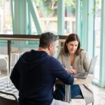 man in black long sleeve shirt sitting on chair beside woman in black and white stripe